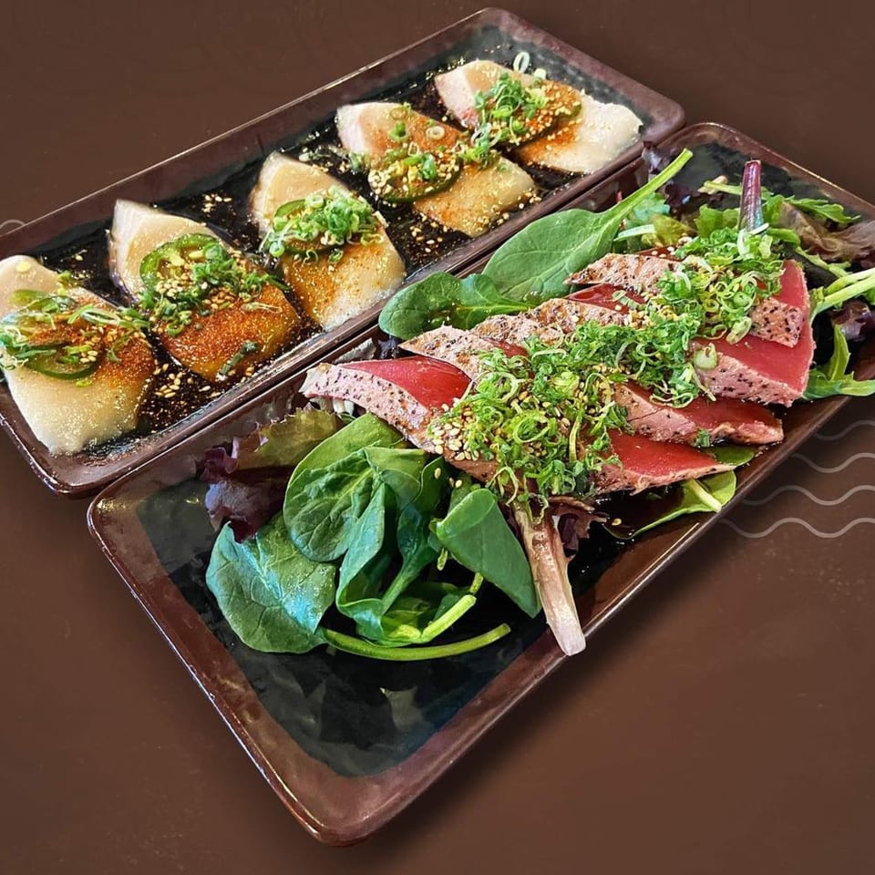 Two rectangular plates of Japanese food, one with seared tuna and greens, the other with white fish.