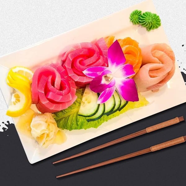 Sashimi platter with tuna, salmon, and white fish, garnished with a purple orchid and lemon.